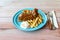 BBQ pork ribs, onion rings, french fries and coleslaw in blue plate on table