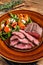 BBq roasted Oyster Top Blade or flat iron roast beef meat steak on a plate with salad. Wooden background. Top View