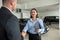 bbusiness client shaking hands with sales agent in suit after buying a car in showroom