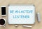 Be An Active Listener, message on whiteboard, smart phone and coffee on table.