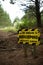 Be aware beekeeping activity ahead yellow and black sign warning sign beside an unpaved road track in Riverhead Forest, Kumeu, New