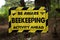 Be aware beekeeping activity ahead yellow and black sign warning sign beside an unpaved road track in Riverhead Forest, Kumeu, New