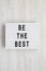 `Be the best` words on a light box on a white wooden background. Flat lay, overhead, top view