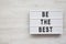 `Be the best` words on a lightbox on a white wooden background. Flat lay, overhead, top view. Copy space