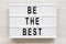 `Be the best` words on a modern board on a white wooden surface. Flat lay, overhead, top view. Close-up