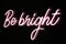 Be bright phrase in pink flashing neon letters over black background.