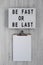 `Be Fast or Be Last` on a lightbox, clipboard with blank sheet of paper on a white wooden surface, top view. Flat lay, overhead,