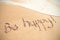 Be happy text written on sand