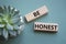 Be honest symbol. Wooden blocks with words Be honest. Beautiful grey green background with succulent plant. Business and Be honest