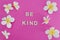 Be Kind message on pink background surrounded by flowers, concept of positive behaviours