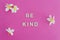 Be Kind message on pink background surrounded by flowers, concept of positive behaviours