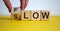 Be slow or in the flow. Male hand turns a cube and changes the word `slow` to `flow`. Beautiful yellow table, white background