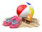 Beach accessories for relaxing. Sunscreen bottle, flip flops, sunglasses and ball onthe sand.