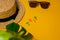 Beach accessories: straw hat, sunglasses, the inscription trip and a wide leaf of a monstera plant for shade on a bright yellow