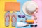 Beach accessories. Various creams, glasses, hat and towel with on a colored background. Top view. Flat Lay.