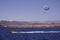 Beach activity: parasailing, high-speed boat pulls a man on a parachute. Sea and mountains on the background