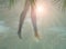 Beach background with blurred silhouettes of female legs, palm leaves and sand.