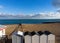 Beach bathing houses beach changing booths / beach huts, rocky beach and sea against blue sky and clouds.