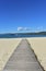 Beach in a bay with bright sand, blue water and boardwalk. Galicia, Spain. Sunny day, blue sky.