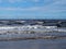 Beach at blundell flats in southport with waves braking on the beach and the wind turbines at burbo bank visible in the