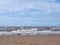 The beach at blundell flats in southport with waves breaking on the beach and the wind turbines at burbo bank visible in the