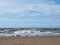 the beach at blundell sands in southport with waves braking on the beach and the wind turbines at burbo bank visible in the