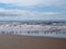 Beach at blundell sands in southport with waves braking on the beach and the wind turbines at burbo bank visible in the