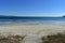 Beach with boardwalk. Clear water with foam. Sunny day, blue sky. Galicia, Spain.