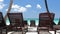 Beach calm scene with sunbeds under coconut palms close to Caribbean sea