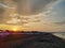 Beach chairs and sunshades parasols aligned on sandy beach during early morning sunrise next to sea with colorful sky