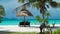 Beach chairs, umbrella and palms on the beach. Longtail local boat passing by. Koh Lipe Island, Thailand, Asia