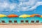 Beach chairs and umbrellas vacation background - colorful parasols lined up on sand of Sint Maarten beach, Dutch Antilles,