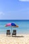 Beach chairs under colorful umbrella on the sand beach looking at the clean blue sea