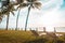 Beach chairs under the palm tree viewing the sunset