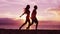 Beach couple on honeymoon walking romantic holding hands at sunset in silhouette