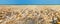 Beach covered with shells and sea on background. Panoramic view.