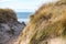 Beach crossing in Denmark by the sea. Dunes, sand water and clouds on the coast