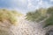 Beach crossing in Denmark by the sea. Dunes, sand water and clouds on the coast