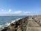 Beach with crystal clear water of the Mediterranean Sea next to a stone walkway and the city of BenicÃ¡sim-BenicÃ ssim, in Castell