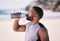 Beach, exercise and man drinking water after running, workout or cardio fitness for health. Hydration, drink and thirsty