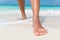 Beach feet closeup - woman walking in water waves