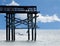 The beach fishing pier has a flock of pelicans fly by the end of the wood structure