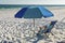 Beach folding chair under a blue umbrella with view of ocean in Destin Florida