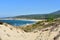 Beach with forest, big sand dunes with vegetation and blue sea with waves and foam. Blue sky, sunny day. Galicia, Spain.