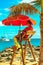 Beach holidays and travel. Lifeguard on the beach under a red umbrella and palm tree.
