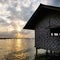 Beach hut standing against sunset sky