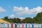 Beach huts with steam train on stone viaduct against blue sky.