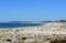 Beach with lake, vegetation in sand dunes and lighthouse. Clear water with waves and foam. Green, blue and turquoise colours. Blue