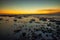 Beach during low tide. Amazing seascape. Stones covered by water. Sunset time. Golden hour. Slow shutter speed. Soft focus.