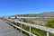 Beach with mountain, lake and wooden boardwalk. Rocks, bright sand and turquoise water. Sunny day, blue sky, Galicia, Spain.